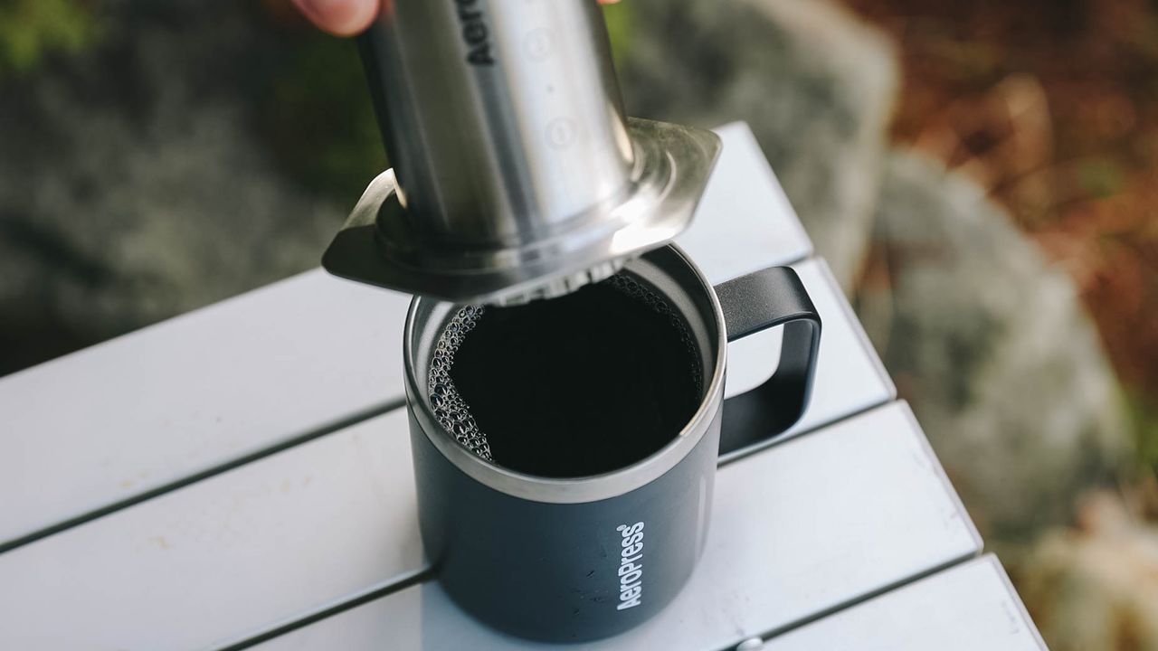 Person using AeroPress Steel coffee maker outdoors