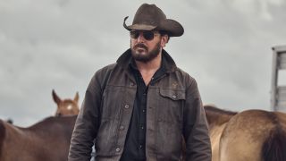 Cole Hauser as Rip Wheller walking in front of horses while wearing a cowboy hat and sunglasses.