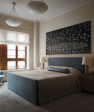 bedroom with blue bedframe and artwork on wall and pendant light