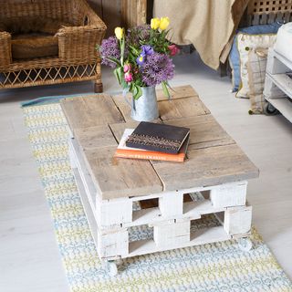 Pallet coffee table on patterned rug next to wicker chairs