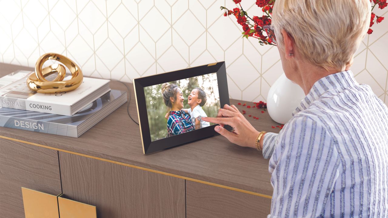 A woman looking at the best digital photo frame, the Nixplay