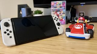 Nintendo Switch OLED with Mario Kart racing car and game in the background