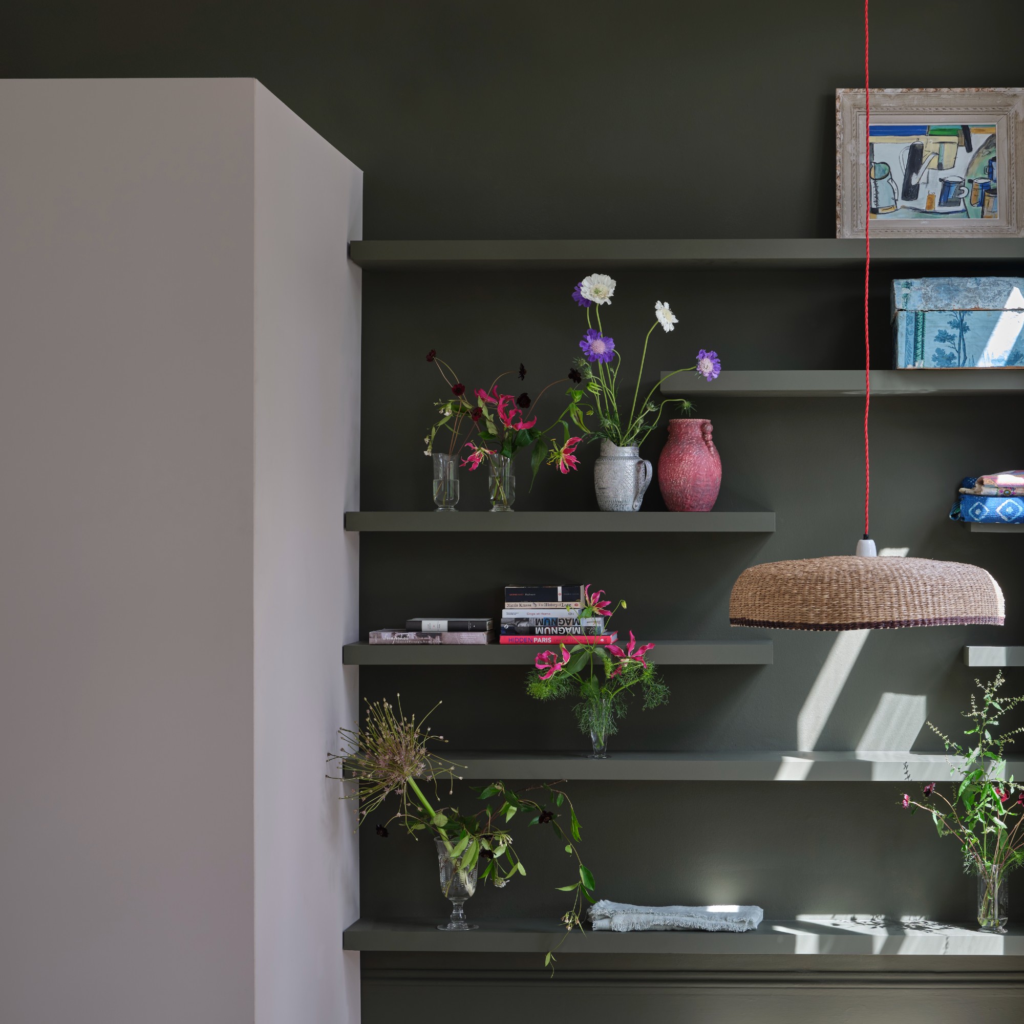 Shelves with flower vases that correspond to the panel in the dark green painted on the wall with the panel next to it in Farrow & Ball -Jakobsmussel