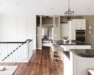 Modern Shaker style, open plan kitchen, with white Jacobean style wall paneling up stair wall.
