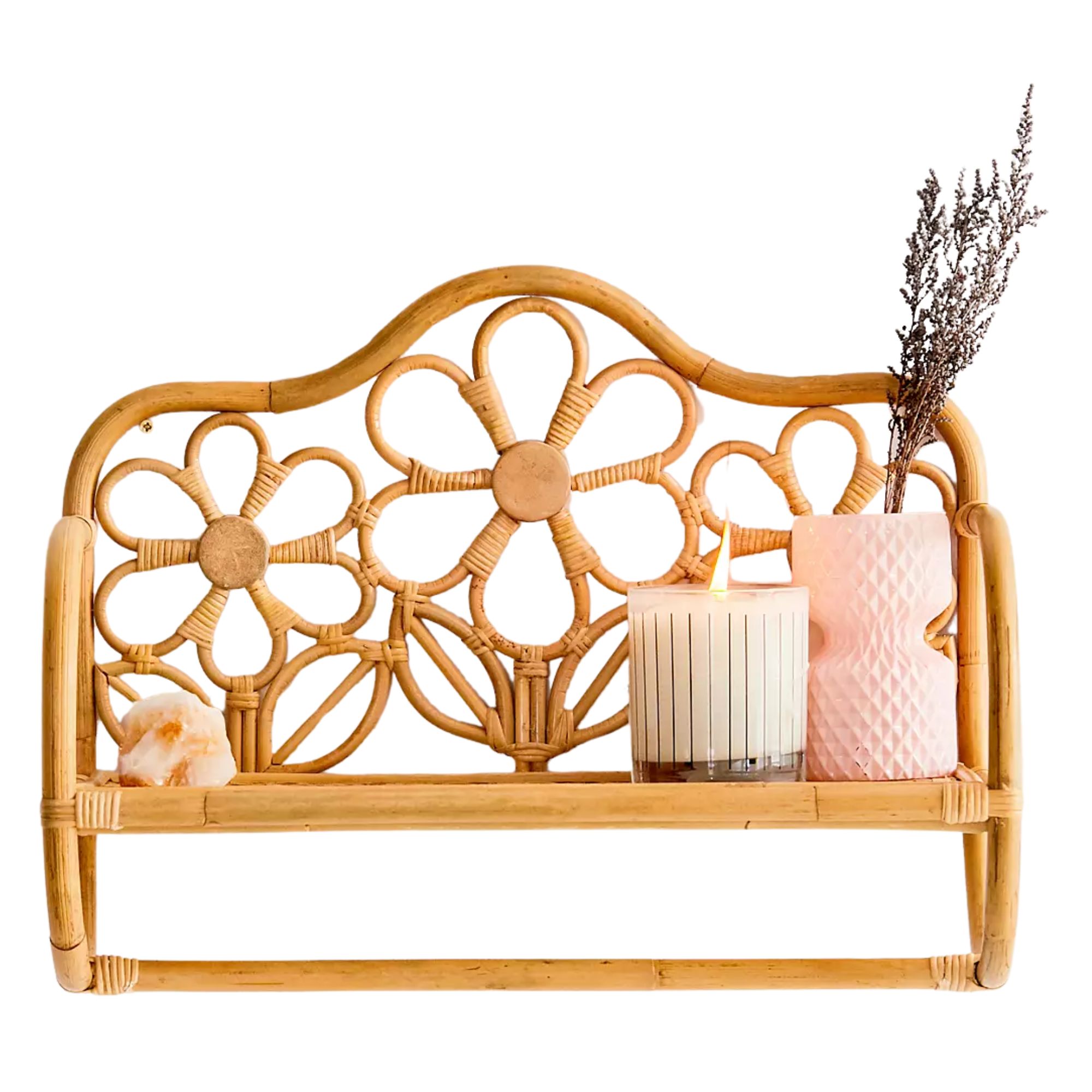 Floral rattan shelf with a crystal, lit white candle with black stripes, and pink hourglass-shaped base with a sprig of dried lavender.