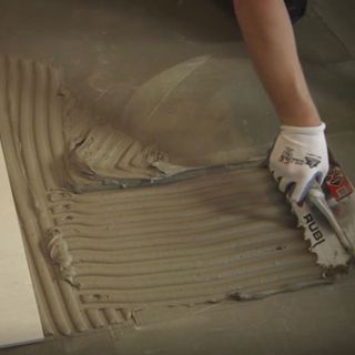 applying adhesive for floor tiles