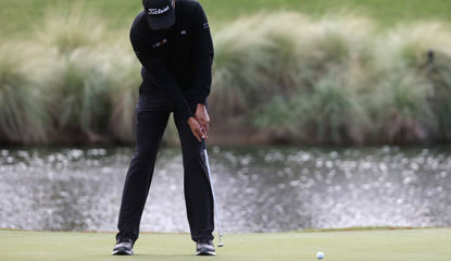 Joseph Bramlett strikes a putt whilst wearing a black polo shirt