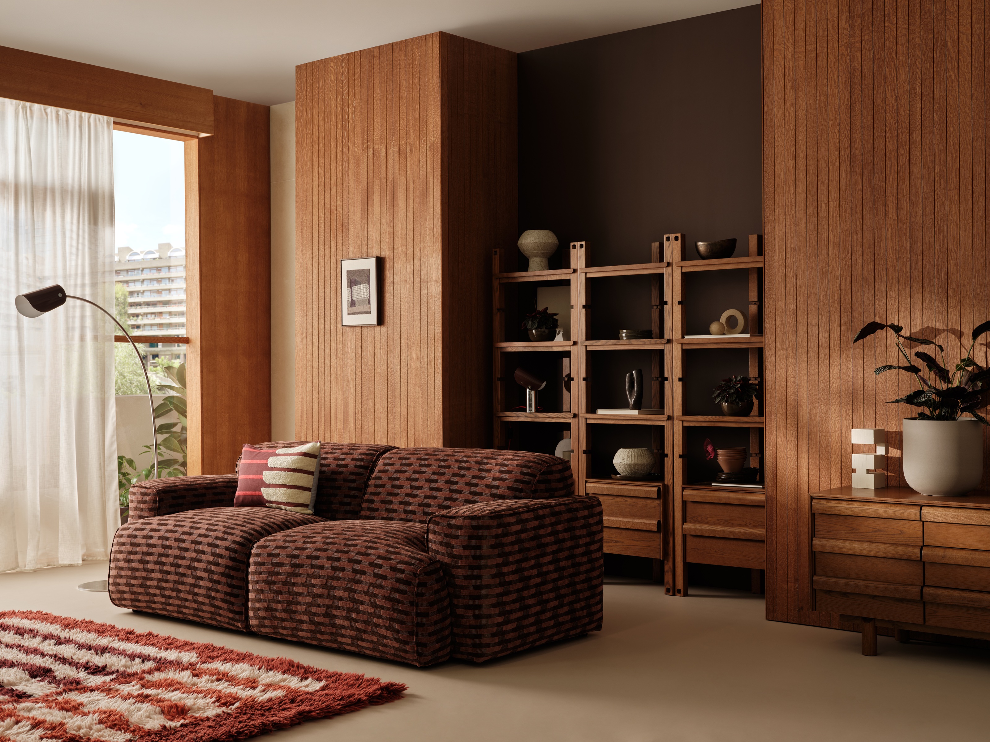 a mid century living room with timber wall paneling, shelves, and a textured patterned sofa