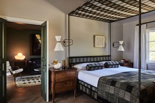 bedroom with neutral paint color on walls, french doors opening to living room, and patterned canopy over the bed