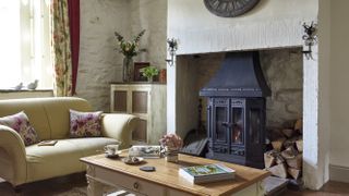 Living room with coffee table and log burning fireplace and floral cushions and curtains