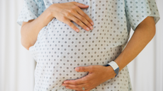 Pregnant woman in hospital gown holding bump