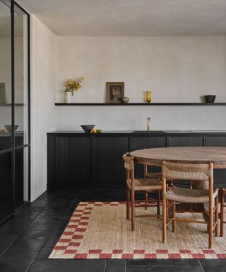 minimalist black kitchen with a rattan and checkerboard rug