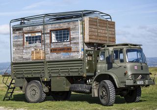 green lorry with sloping roof house shed on grass field