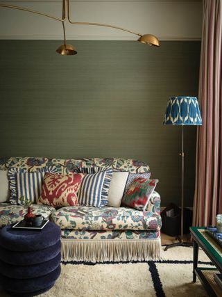 A living room with a patterned sofa, patterned scatter cushions, and a patterned floor lamp with a pleated shade