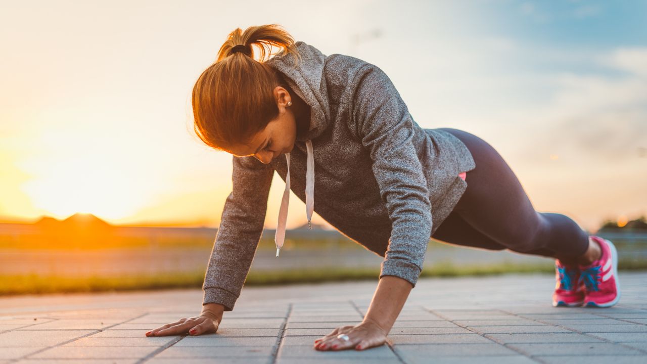 A woman performing a push-up outside