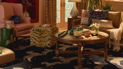 Eclectic, pattern-filled living room featuring a tiger print ottoman, wooden coffee table, and zebra motif area rug