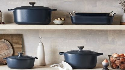 One of the luxury Christmas gifts I'll be buying this Black Friday: Le Creuset French Oven alonside other Le Creuset pans and dishes across two shelves in a kitchen