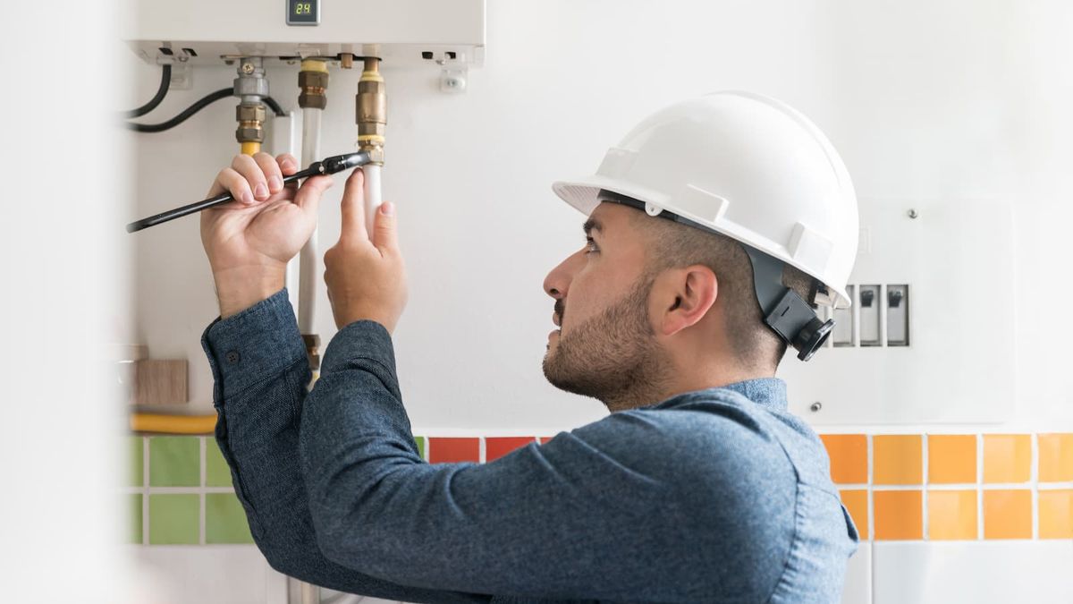 Repairman installing a natural gas boiler at a house using a wrench