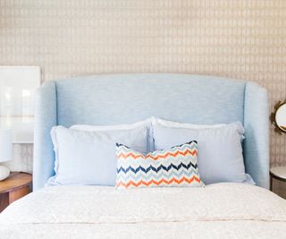 bedroom with cream patterned wallpaper and pale blue bedhead