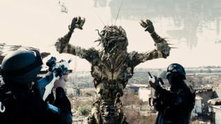 District 9 screengrabs, showing alien held at gunpoint by troops