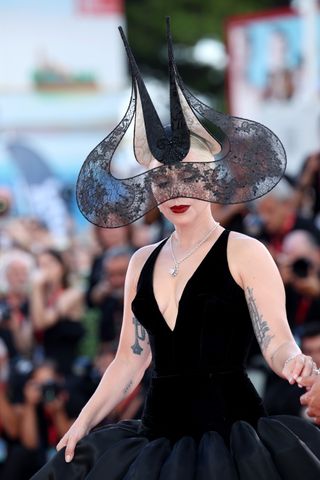 Lady Gaga wears a black lace headpiece by Philip Treacy at the Joker premiere.