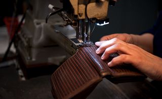 An artisan repairs a woven leather bag