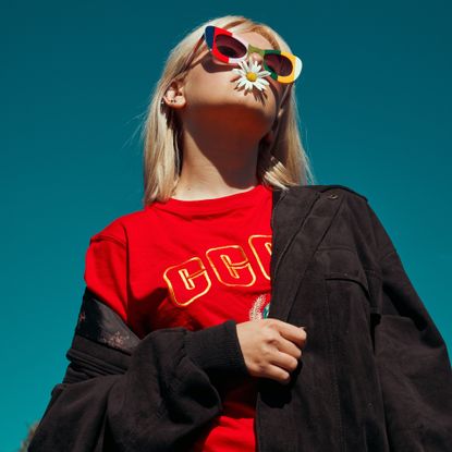 Model with sunglasses on and flower in her mouth