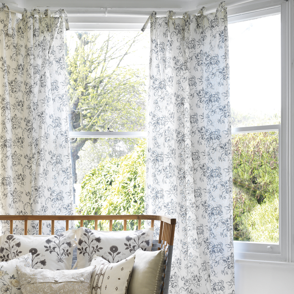 white room with floral curtains and pillows