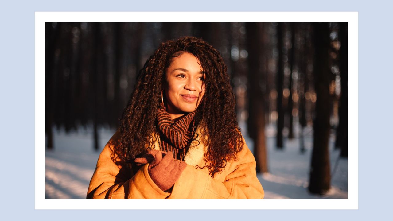 woman outside in the sun in a wintery forest; meant to symbolize the winter solstice