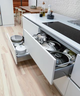 White saucepan draws illustrating modern kitchen design in a white scheme.
