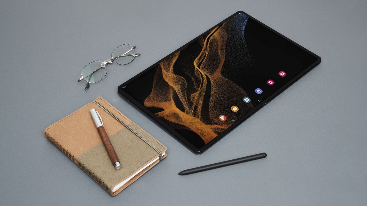 Samsung Galaxy Tab S8 Ultra on a grey table with a notepad and glasses