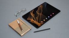 Samsung Galaxy Tab S8 Ultra on a grey table with a notepad and glasses