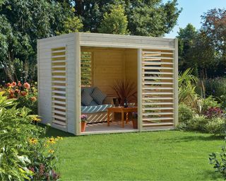 Light wood garden shed in cube design, with shuttered front and sides.