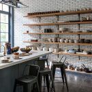 kitchen with open crockery shelve with fruit bowl and white tiles on wall