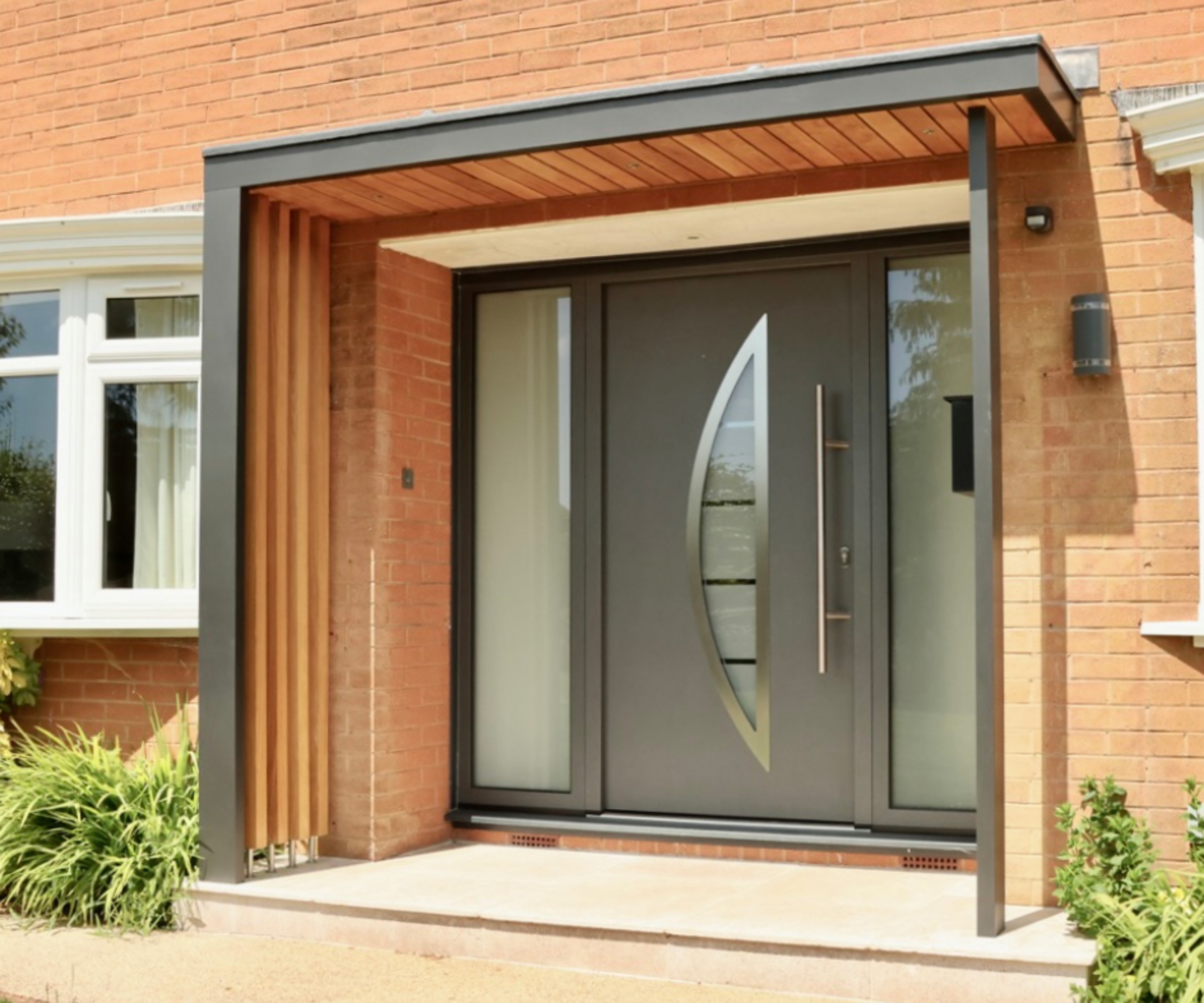 modern oak and grey aluminium framed porch on brick home with modern grey composite front door