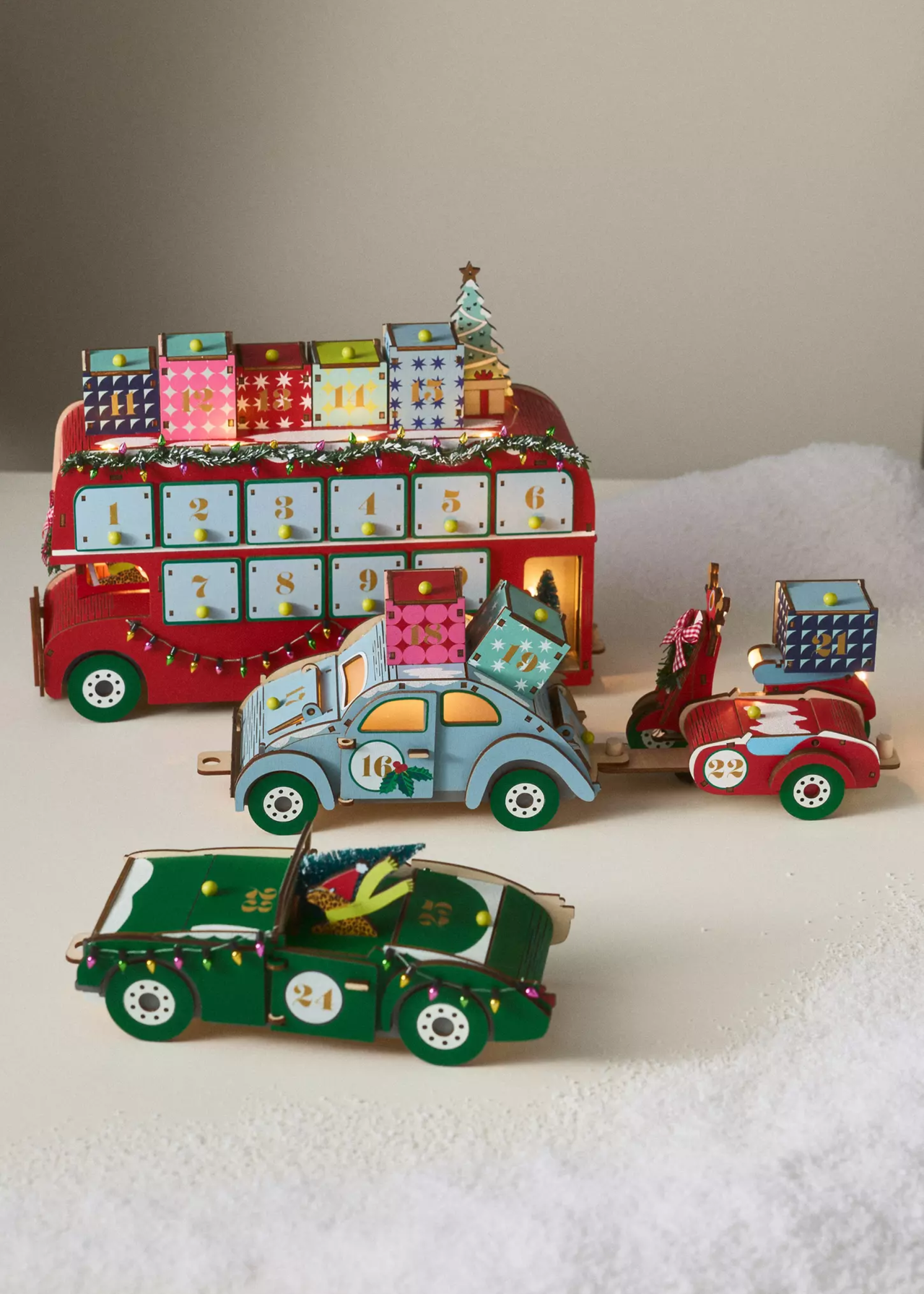 anthropologie christmas advent calendar of a red london bus with windows and presents on top that reveal the pieces to build little cars to travel for christmas