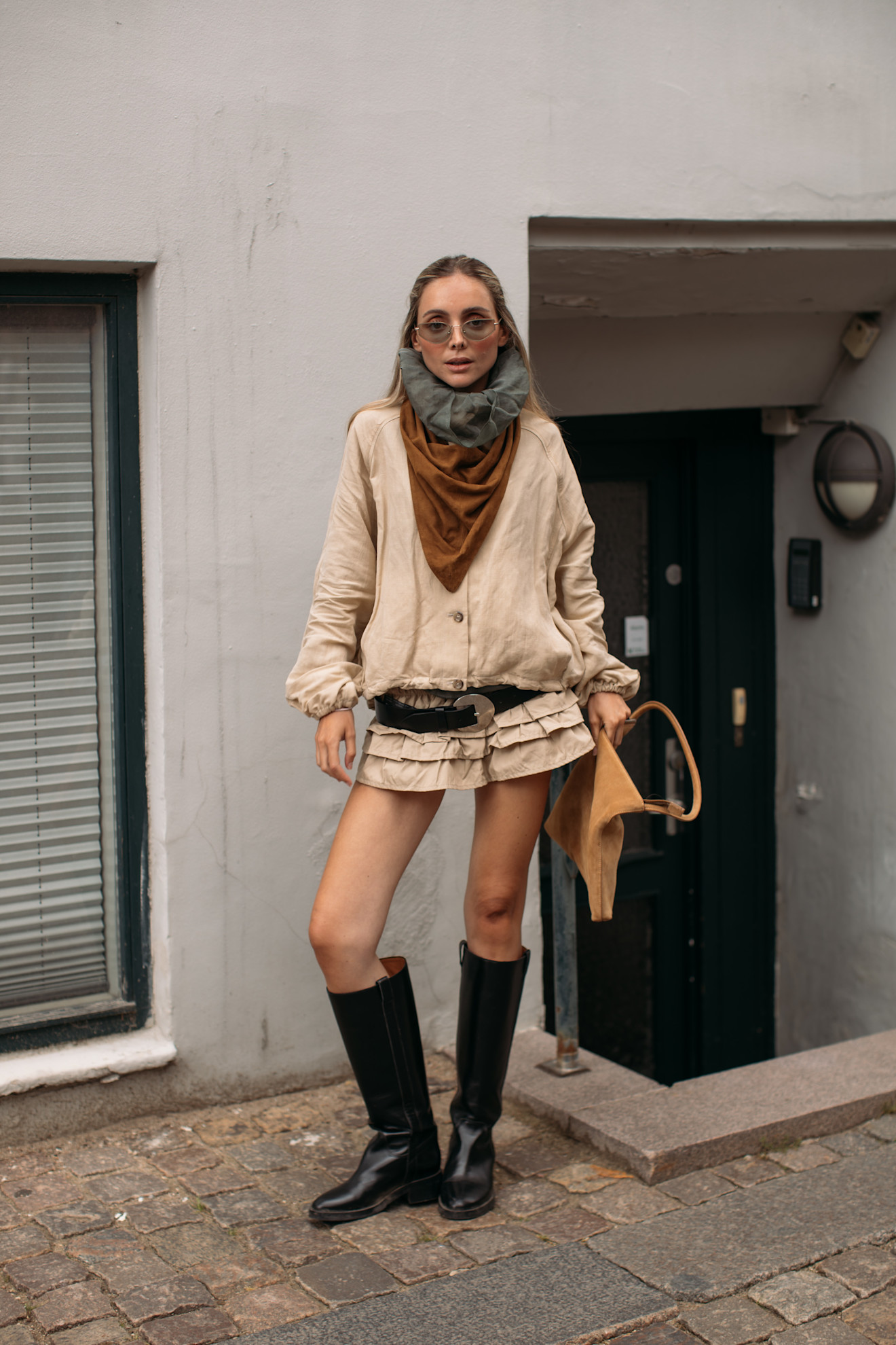 woman wearing knee-high flat boots and a tan mini dress