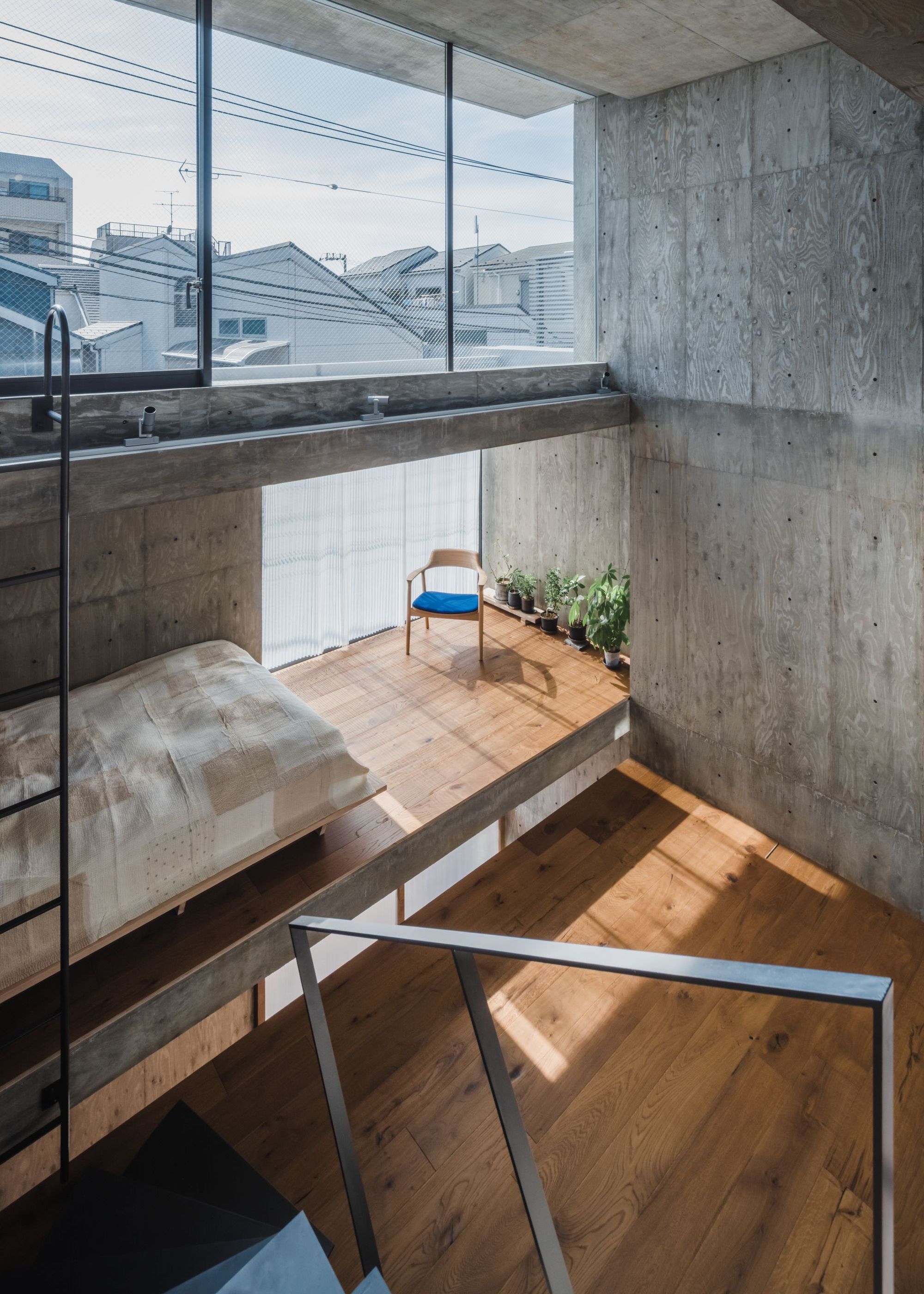 An open multi-layered Japanese home with concrete walls and ceiling, no doors, wood flooring and floating staircases