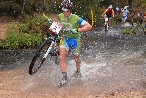 Wolfgang Krenn carries his bike across a river