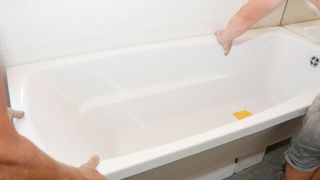 White bath being installed in bathroom against white tiles