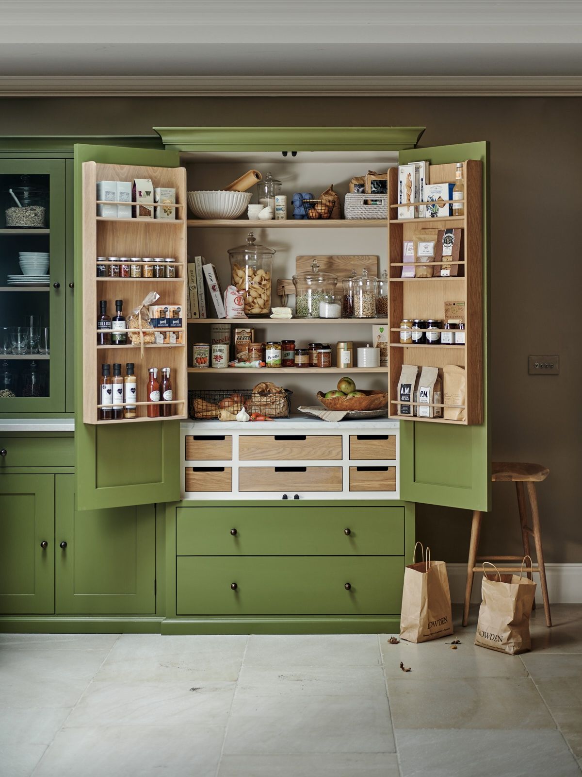 A green larder on a white stone kitchen floor.