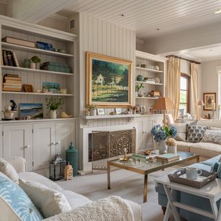 pale painted living room with wooden panelling over walls and ceiling and alcove cupboards