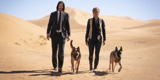 John Wick: Chapter 3 - Parabellum Keanu Reeves and Halle Berry walk through the desert with two dogs