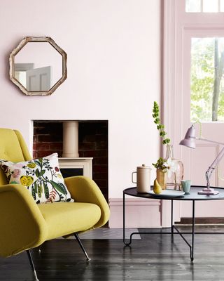 living with very pale pink color on walls in living room with woodburning stove and velvet lime green armchair