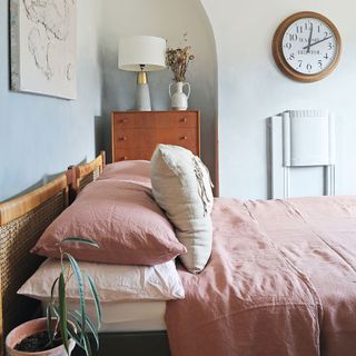 Bedroom with double bed with pink and beige bedding, clock and art on wall