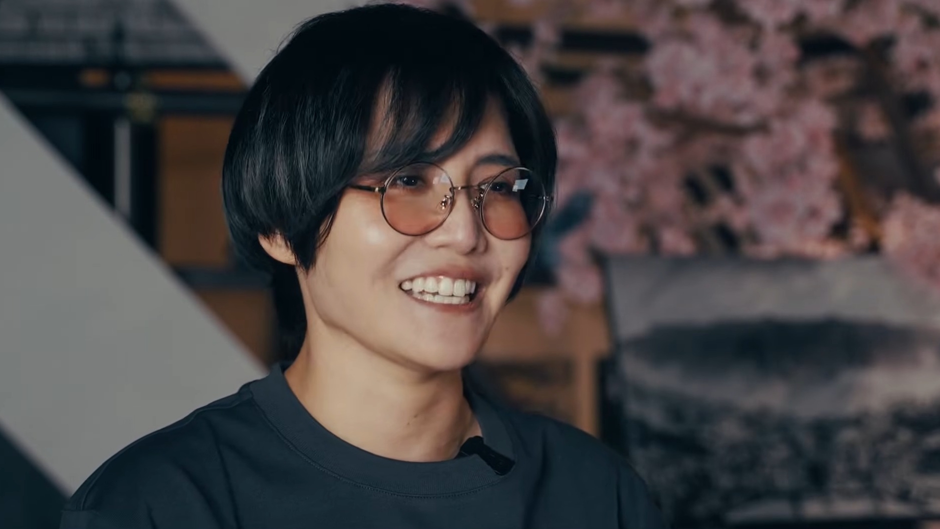 Ikumi Nakamura smiles wearing orange-tinted round glasses