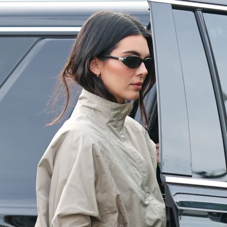 Kendall Jenner attends the 2026 Fanatics Super Bowl Party at Pier 48 in San Francisco, California wearing black capri pants, thong mules, and a track jacket