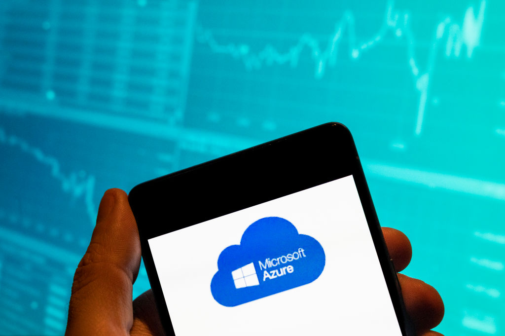 Microsoft, Azure logo is seen displayed on a smartphone with an economic stock exchange index graph in the background