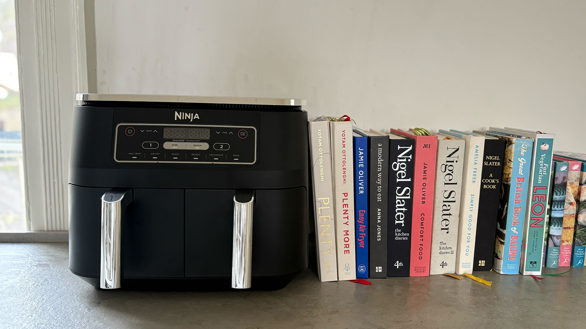 double fronted air fryer on a kitchen countertop next to a stack of books