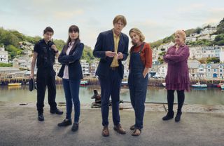 The cast of Beyond Paradise in a group shot on the seafront of Shipton Abbott: Dylan Llewellyn as PC Kelby Hartford, Zahra Ahmadi as DS Esther Williams, Kris Marshall as DI Humphrey Goodman, Sally Bretton as Martha Lloyd and Felicity Montagu as Margo Martins
